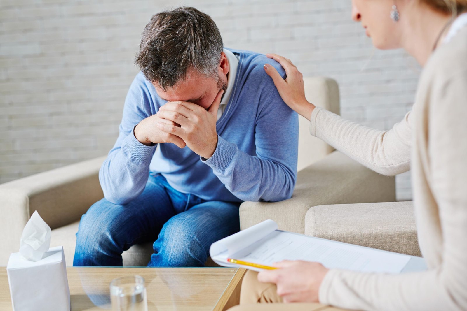 Doctor comforting crying senior patient in hospital room