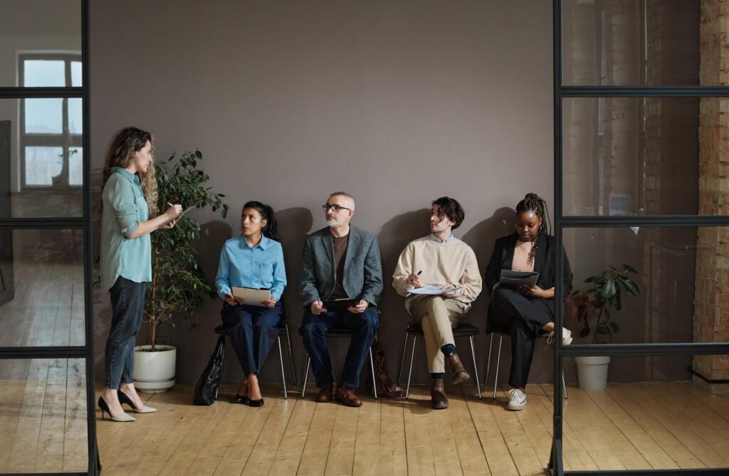 Woman standing and speaking to four seated colleagues in an office.