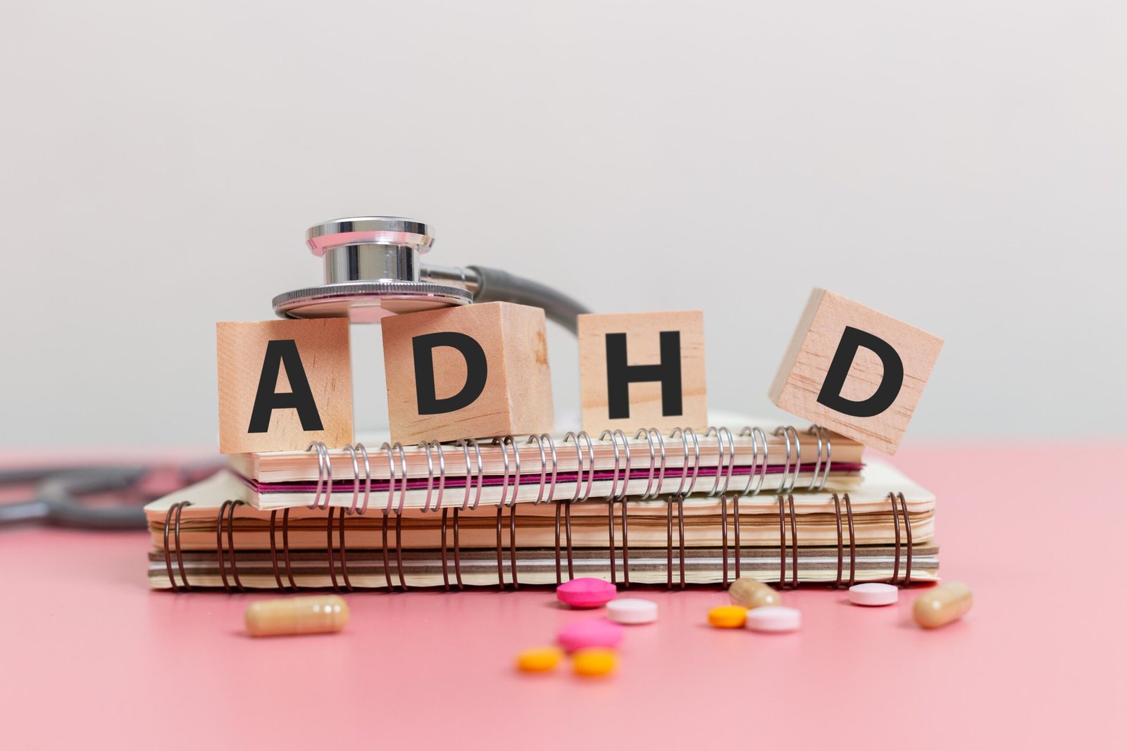 ADHD blocks on notebooks with stethoscope and scattered medication pills.