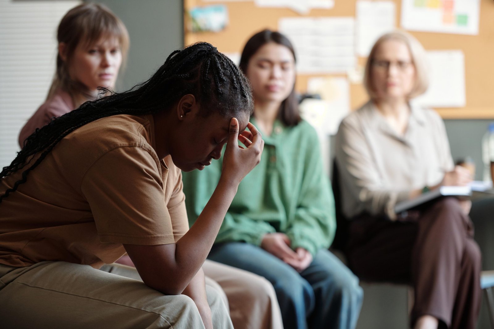 Distressed woman in group therapy holding head while others observe.