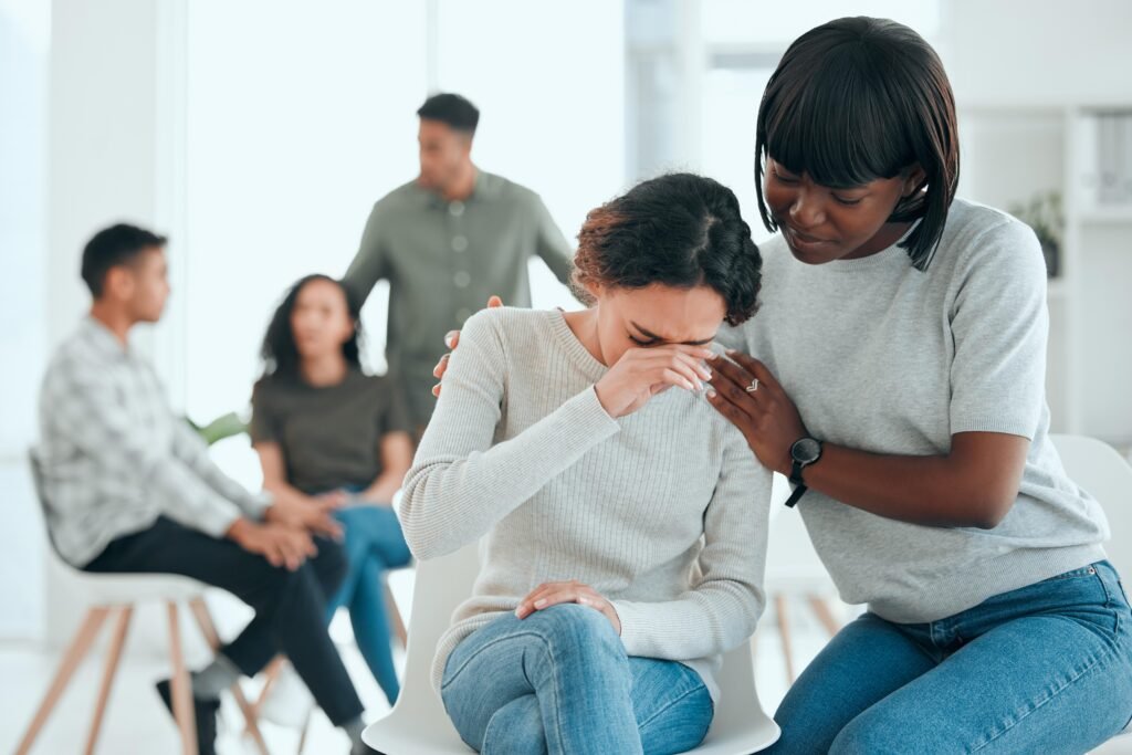 Woman comforting a crying group member during an emotional support meeting.