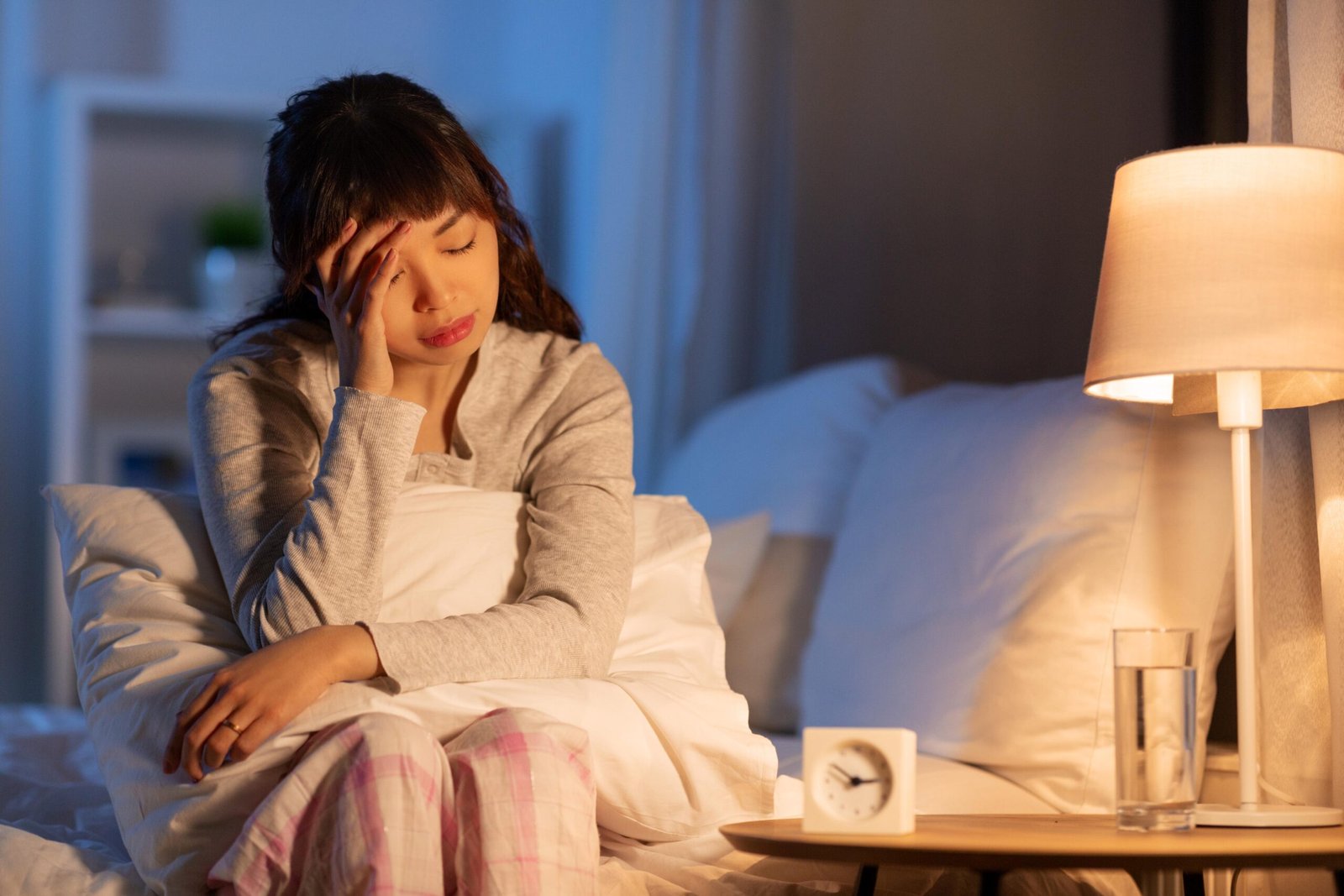 Woman sitting up in bed at night, struggling with insomnia